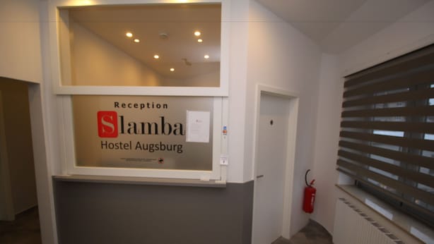 Una recepción con un cartel que dice 'Slamba Hostel Augsburg'.