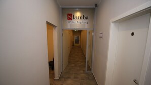 Un pasillo con un letrero que indica 'Slamba Hostel Augsburg' y puertas numeradas 5 y 6.