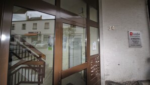 Entrada de hotel con puerta de vidrio, escalera de madera y un letrero que indica la habitación número 34.
