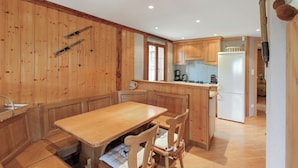 Une cuisine aux murs lambrissés, dotée d’un îlot central, de chaises en bois et d’une table à manger.