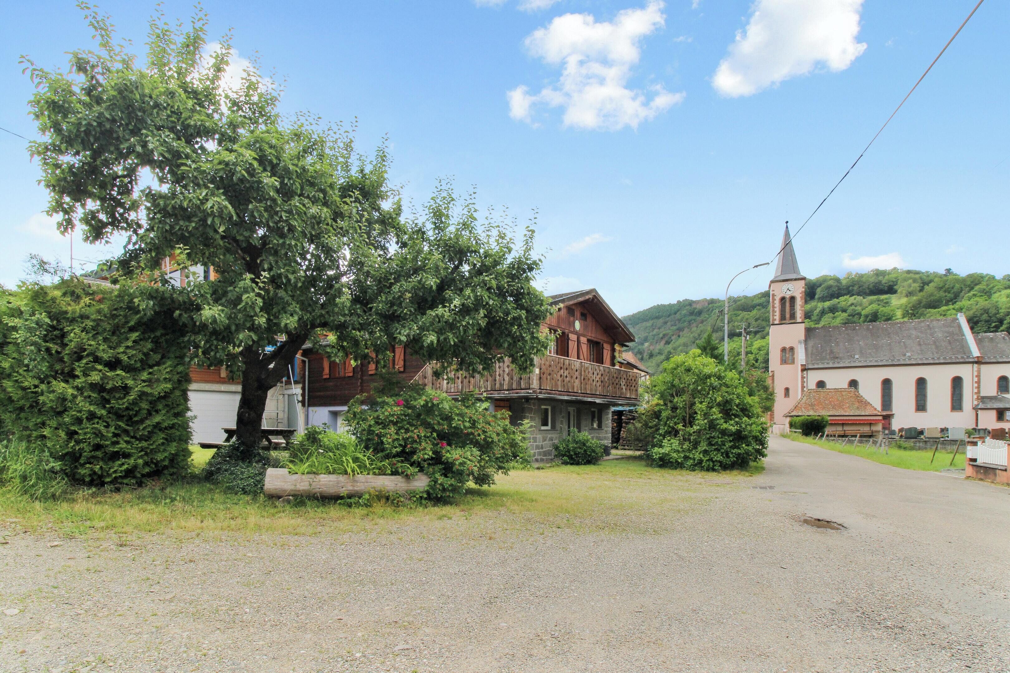 A rural road with a wooden house and a church.