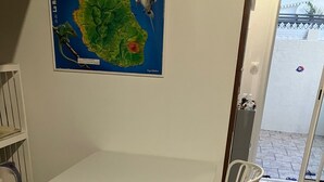 A small dining area with a white table and chairs, a map on the wall, and a view of the outside through a glass door. - Maisonnette with mezzanine, air conditioning, secure parking, wifi internet, Rated 3 stars. (st pierre)