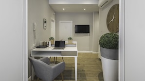 Una habitación moderna y luminosa con un escritorio blanco, una silla gris y un reloj de pared grande.