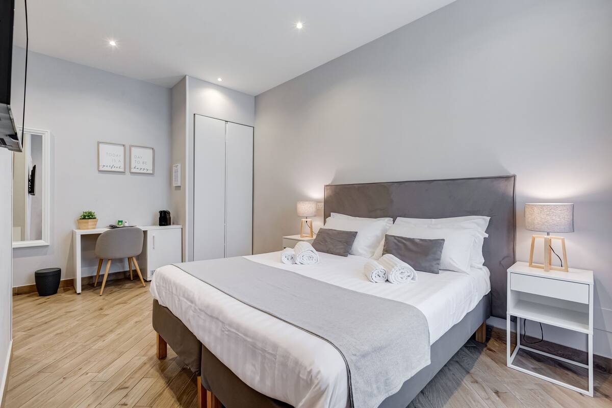 A modern hotel room with a large bed, bedside tables, a desk, and a chair.