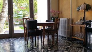 A dining area with a table and chairs, a radiator, and a glass cabinet with wine glasses. - Bed and Breakfast Exterlaer (Antwerp)