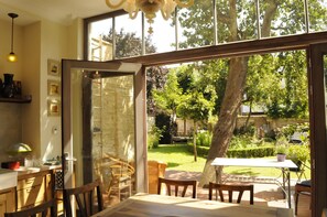 A room with a large glass door leading to a garden, wooden furniture, and a table with chairs. - Bed and Breakfast Exterlaer (Antwerp)
