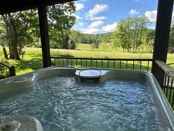 Ein Whirlpool mit Blick auf ein grünes Feld und Bäume.
