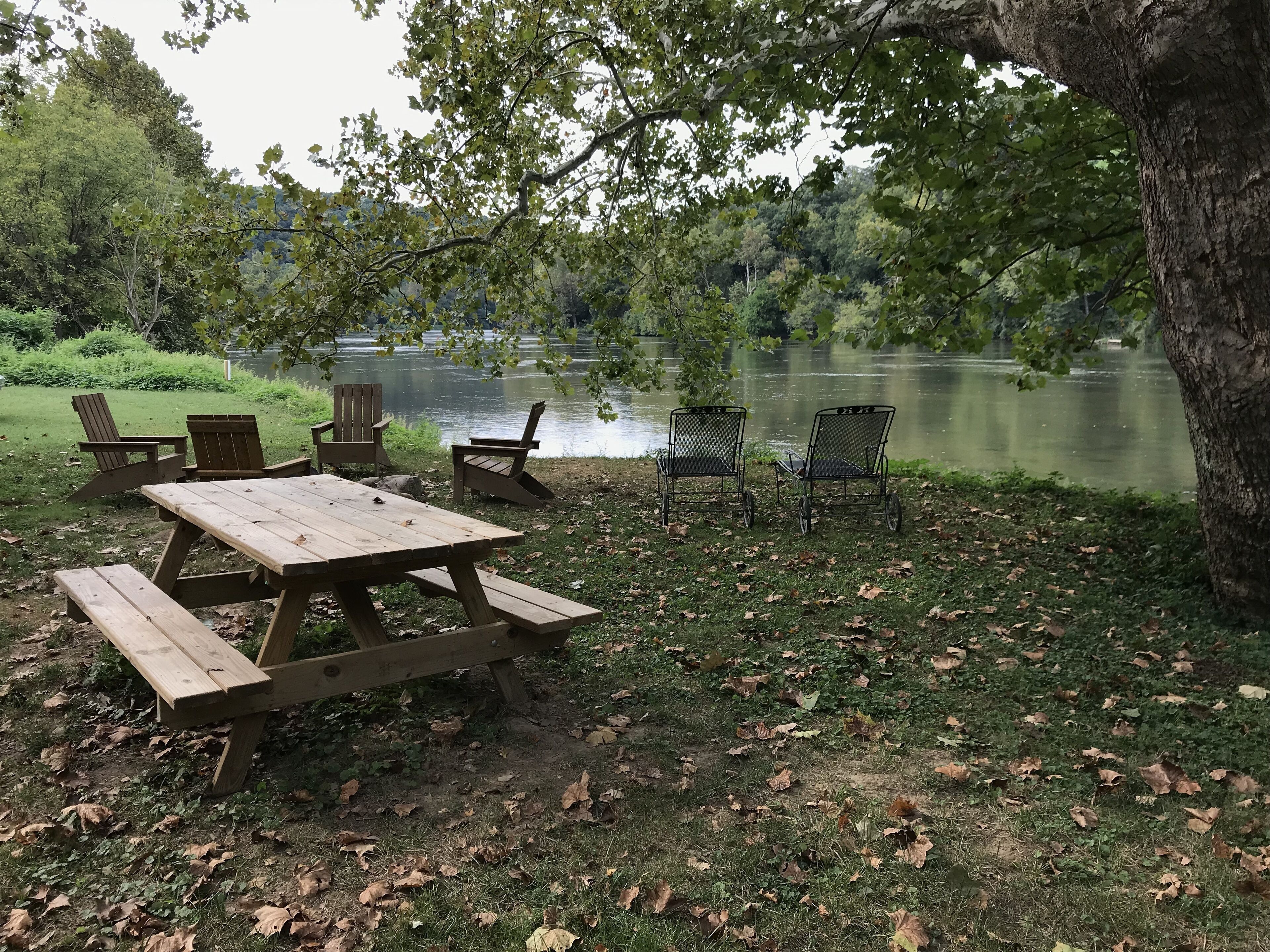 Una mesa de picnic con bancos y sillas junto a un lago.