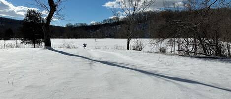 A snow-covered landscape with a clear sky and a signpost in the distance.