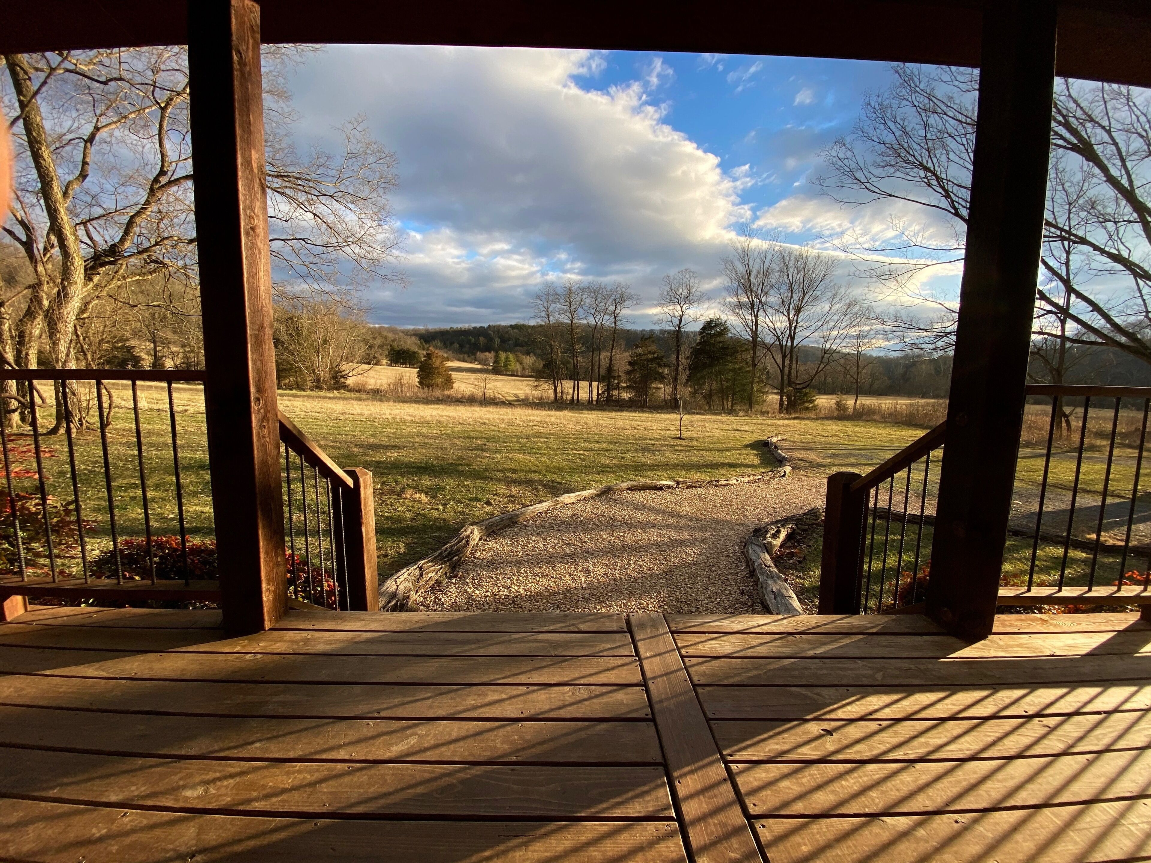 Una terraza de madera con vistas a un campo cubierto de hierba y árboles.