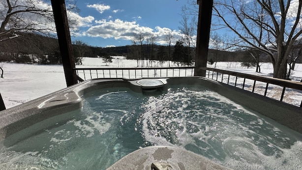 Un jacuzzi con vistas a un paisaje nevado y árboles.