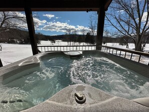 Ein Whirlpool mit Blick auf eine verschneite Landschaft und Bäume.