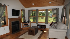Una sala de estar con chimenea, un sofá, un televisor y una estantería.