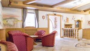 A cozy room with wooden beams, a fireplace, and patterned furniture.