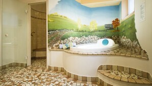 A bathroom with a mosaic floor, a bathtub, and a mural of a landscape.