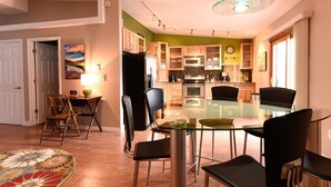 A modern kitchen with wooden cabinets, a glass dining table, and black chairs.