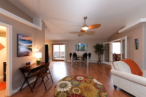 A spacious living room with a ceiling fan, a dining area with a table and chairs, and a sofa with an orange throw. - Hip, Gorgeous and Spacious Loft in the ❤️ of Estes Park on Parade Route (Estes Park)