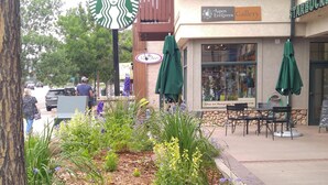 A Starbucks with outdoor seating, a garden area with flowers, and a building with a sign for Aspen Gallery.