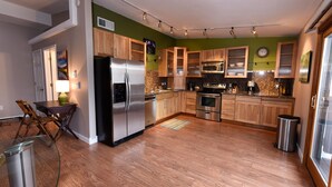 A modern kitchen with wooden cabinets, stainless steel appliances, and a dining area with a table and chairs.