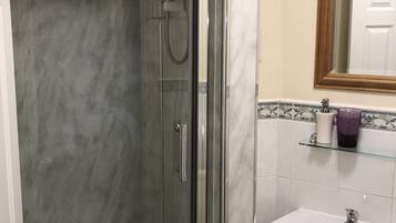 A bathroom with a glass-enclosed shower, a white sink, and a mirror above it.