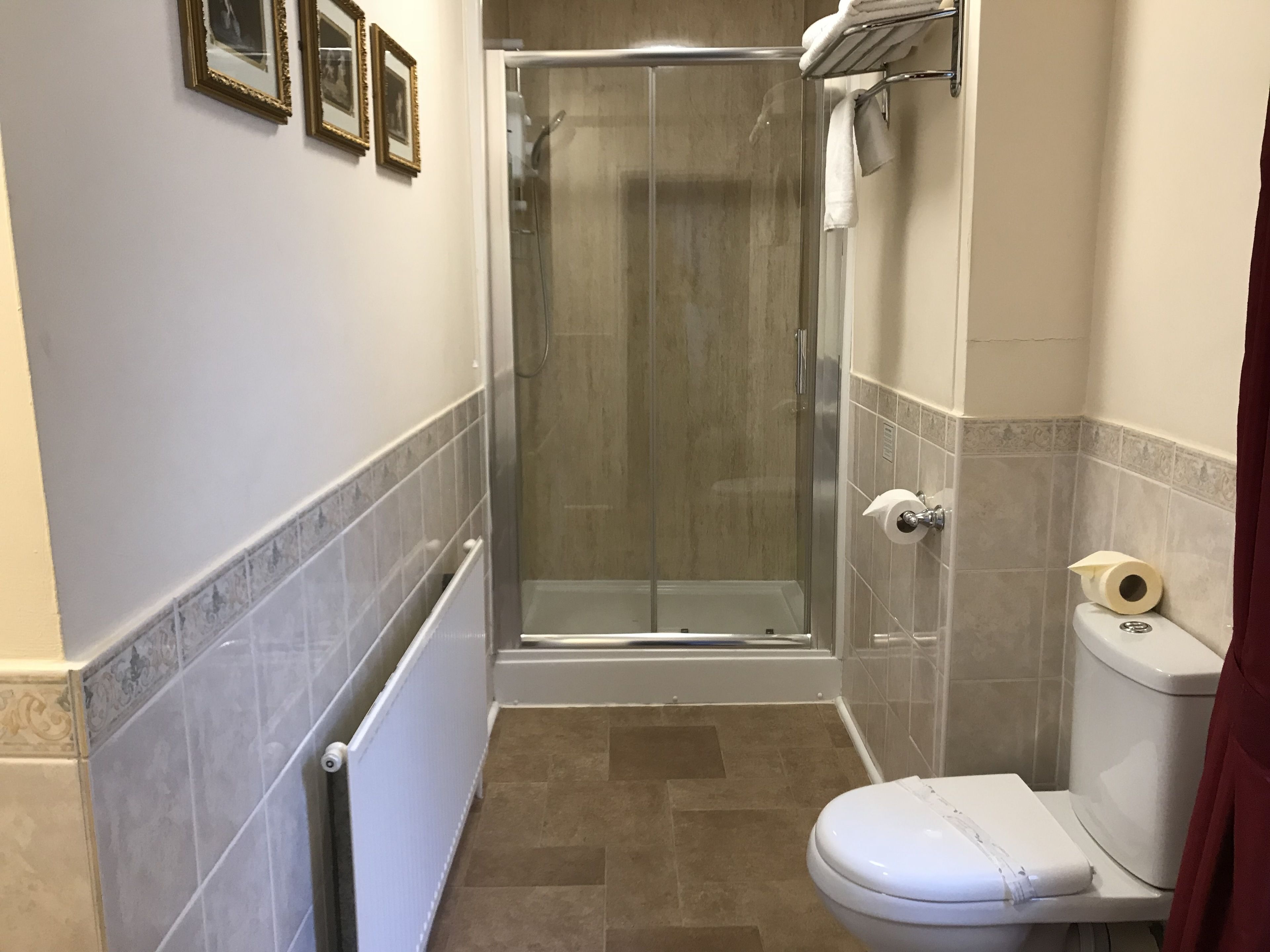 Un bagno con box doccia in vetro, un water e un termosifone.