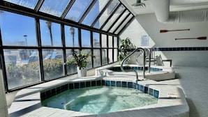 A hot tub with a view of palm trees and a cityscape through large windows. - Newly Renovated kitchen in this 2BR Beachfront Condo on the 6th Floor! (Orange Beach)