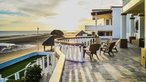 Un balcone con vista sulla spiaggia e sull'oceano, dotato di una zona salotto con sedie e un tavolo.