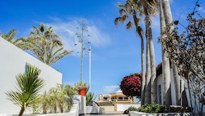 Un edificio moderno con facciata bianca, palme e una scalinata che conduce a un balcone.