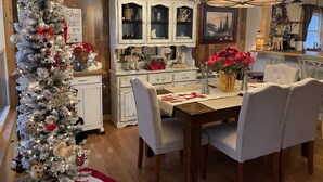 A dining area with a Christmas tree, white cabinets, and a chandelier. - Last Wk of Aug Open!! Enjoy the creek, close to Pigeon Forge (Sevierville)