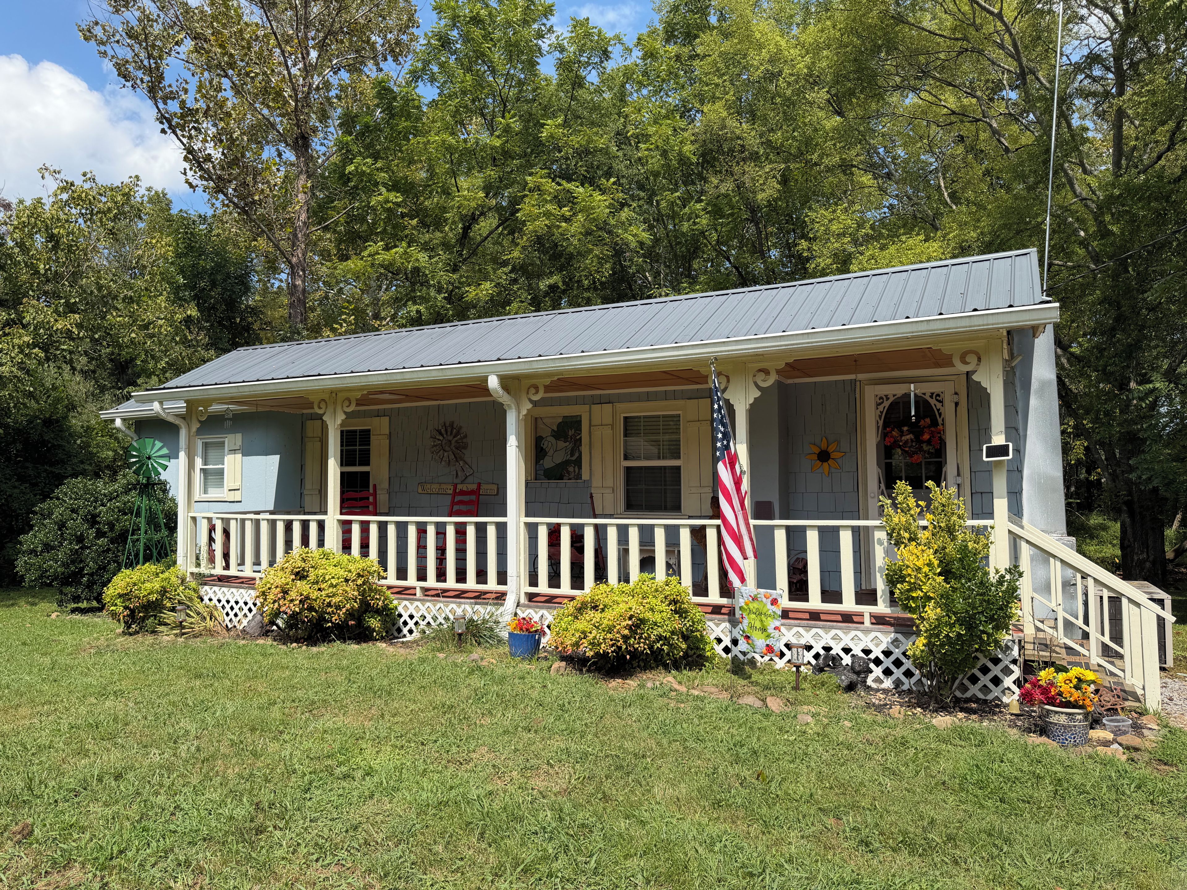 A house with a porch, a windmill, and a flag.