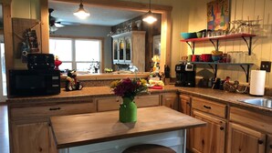 A kitchen with wooden cabinets, a microwave, a coffee maker, and a vase with flowers on the counter. - Last Wk of Aug Open!! Enjoy the creek, close to Pigeon Forge (Sevierville)
