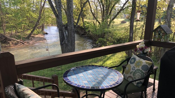 A covered outdoor area with a table and chairs, overlooking a river and greenery. - Last Wk of Aug Open!! Enjoy the creek, close to Pigeon Forge (Sevierville)