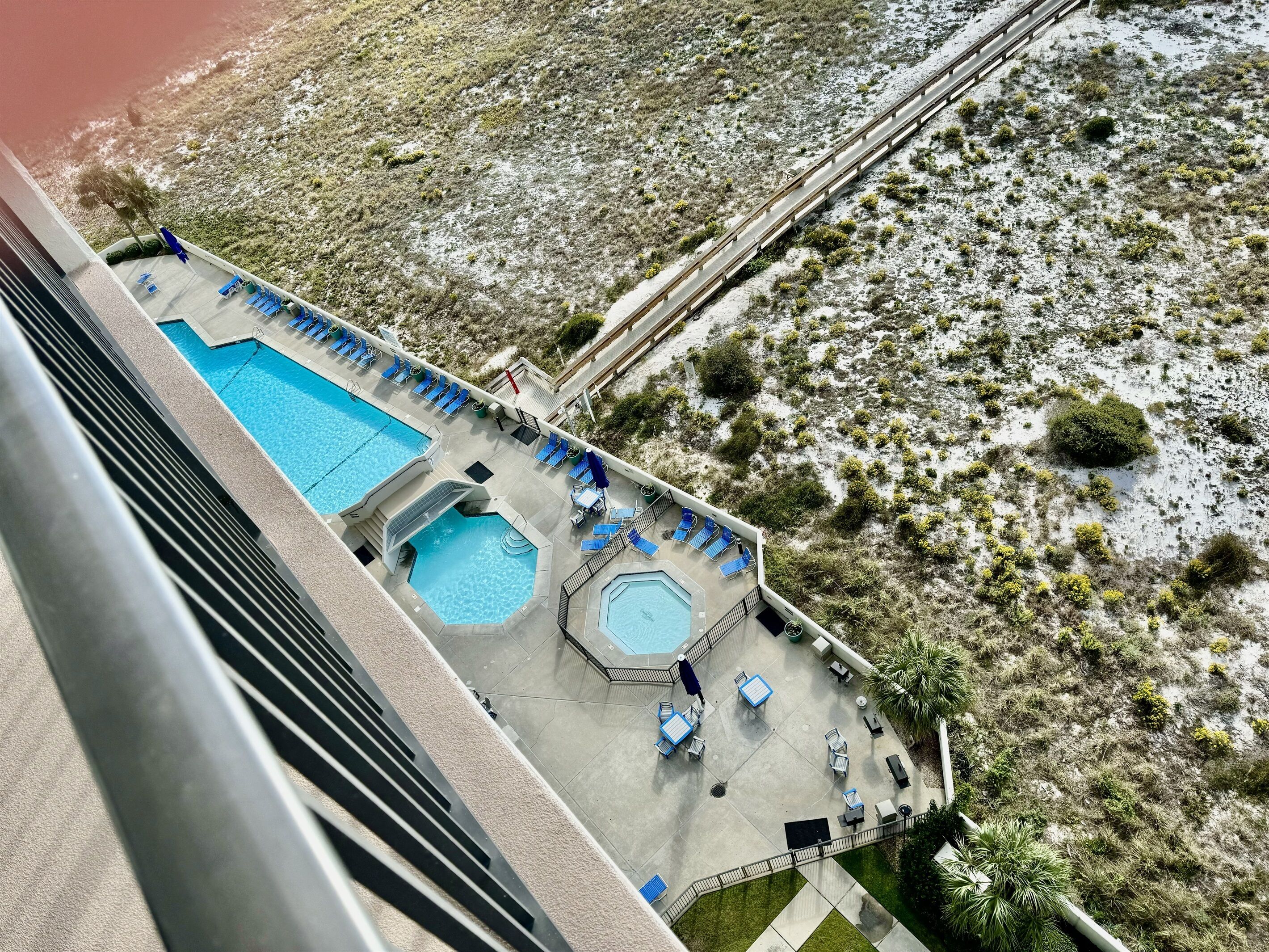 A rooftop pool area with multiple pools and lounge chairs, surrounded by a desert landscape.