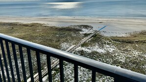 Uitzicht op de kust met een strand, een brug en een hekwerk.