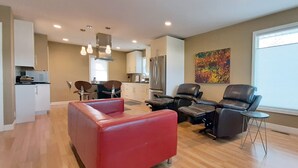 A modern living room with a red sofa, black leather chairs, a small table, and a guitar on the wall. - Recliners. Single Level Living. Walk-in shower. (Rochester)