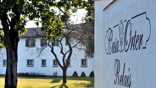 A sign with the text "Casa-Orden Redais" in front of a building with a tree and a lawn. - Casa Orter (Pavia di Udine)