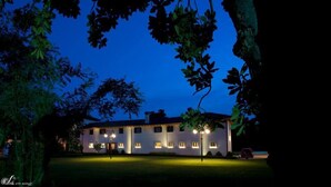 A two-story building with a symmetrical facade, evenly spaced windows, and a well-maintained lawn. - Casa Orter (Pavia di Udine)