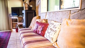 A cozy living room with a sofa, patterned cushions, a television, and a stone fireplace.