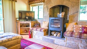 A cozy living room with a stone fireplace, a television on a stand, and comfortable seating.