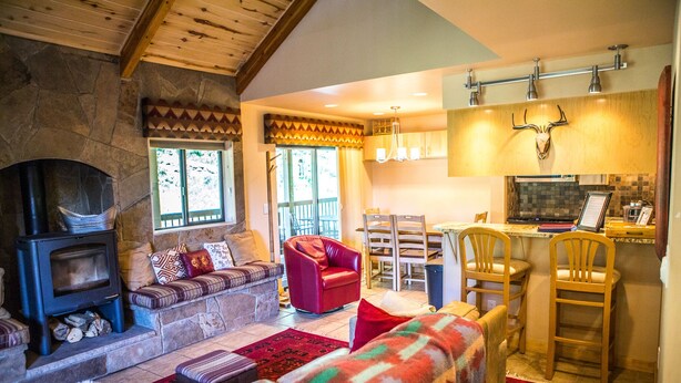 A cozy living room with a stone fireplace, a red leather sofa, and a colorful blanket.