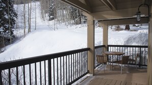 A covered outdoor area with a wooden deck, metal railing, and a table with chairs.