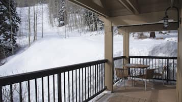 Un espace extérieur abrité, doté d’une terrasse en bois, d’une rambarde en métal et d’une table avec des chaises.