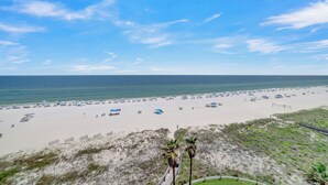 A beach with tents and umbrellas, a sandy shore, and a clear sky. - Summer House 704B by Liquid Life (Orange Beach)