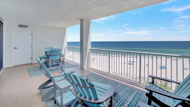 A balcony with blue Adirondack chairs, a table, and a view of the beach and ocean. - Summer House 704B by Liquid Life (Orange Beach)