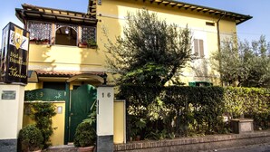 Un edificio amarillo con puerta verde, plantas en macetas y un letrero de casa de huéspedes.