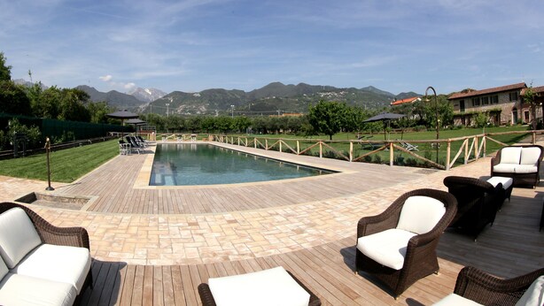 A pool area with wicker furniture and a view of mountains. - Olimagio (Pietrasanta)