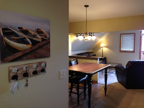 A dining area with a wooden table and chairs, a chandelier, and a painting of boats on the wall.