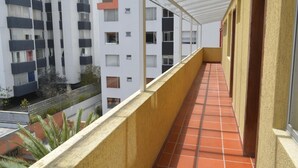 A corridor with a tiled floor, a glass roof, and a yellow wall. - Hotel Casa Kolping Quito (Quito)