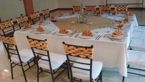 A conference room with round tables, white tablecloths, and chairs with woven headrests. - Hotel Casa Kolping Quito (Quito)