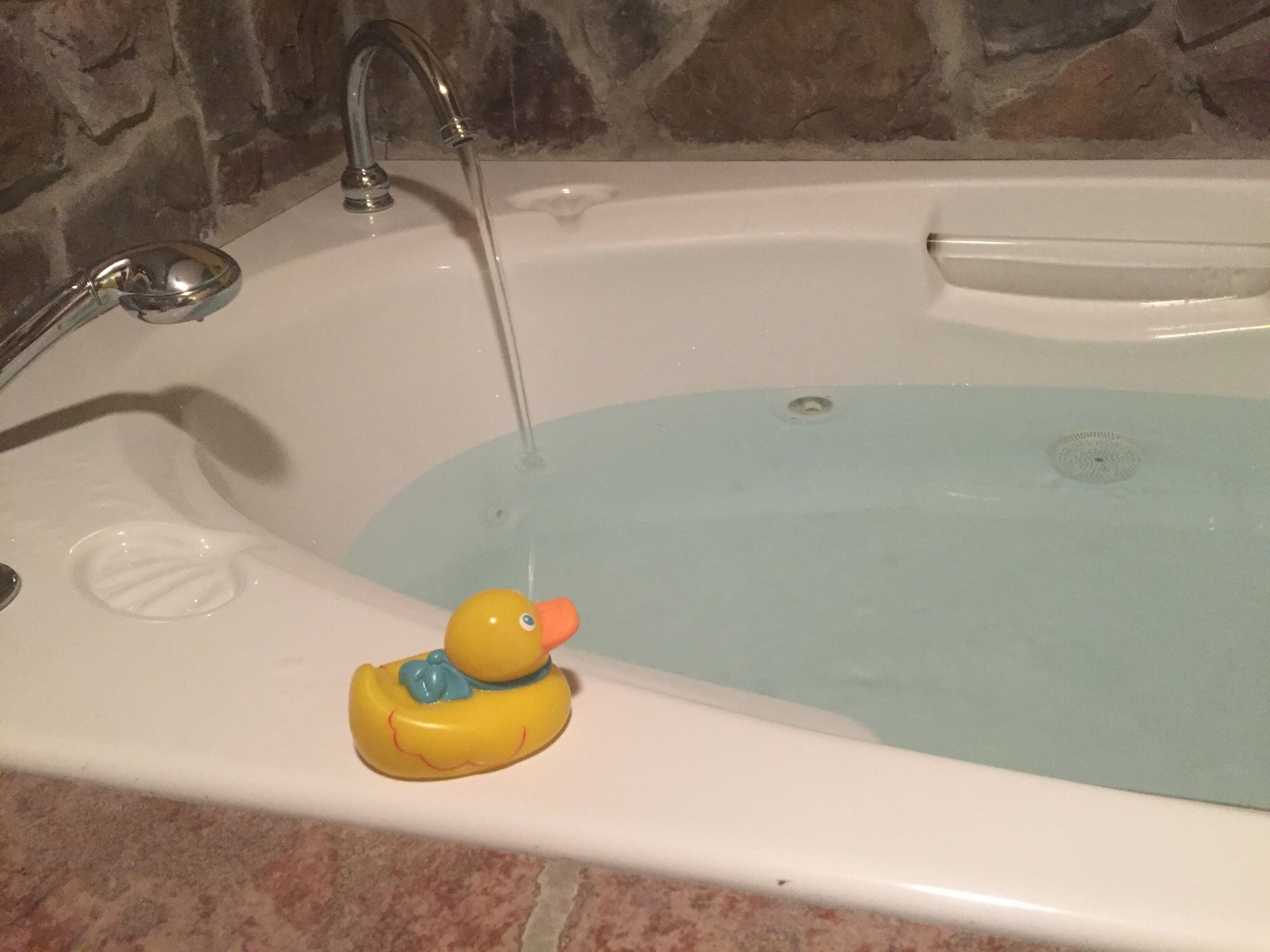 A bathtub with a rubber duck and running water.